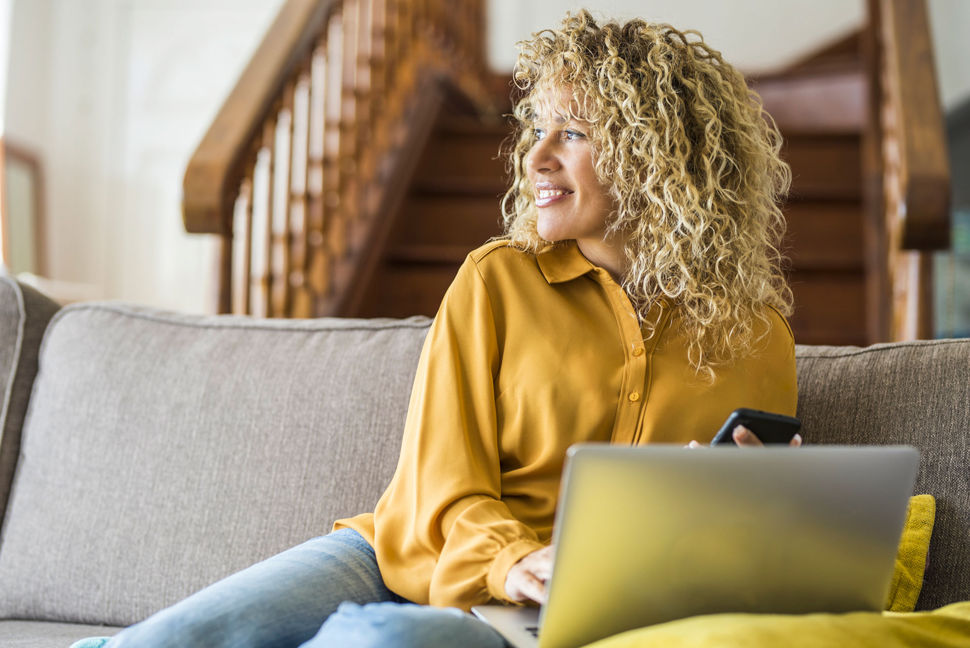 Woman with blonde long curly hair work at home on laptop computer